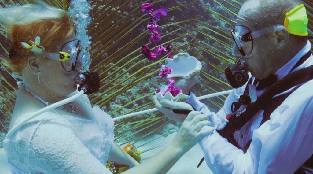 man and woman wearing scuba gear getting married under water