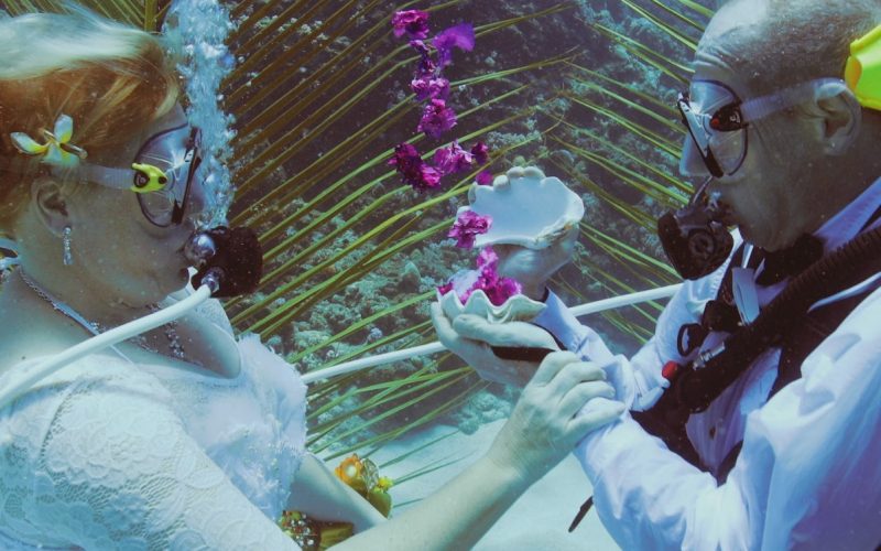 man and woman wearing scuba gear getting married under water